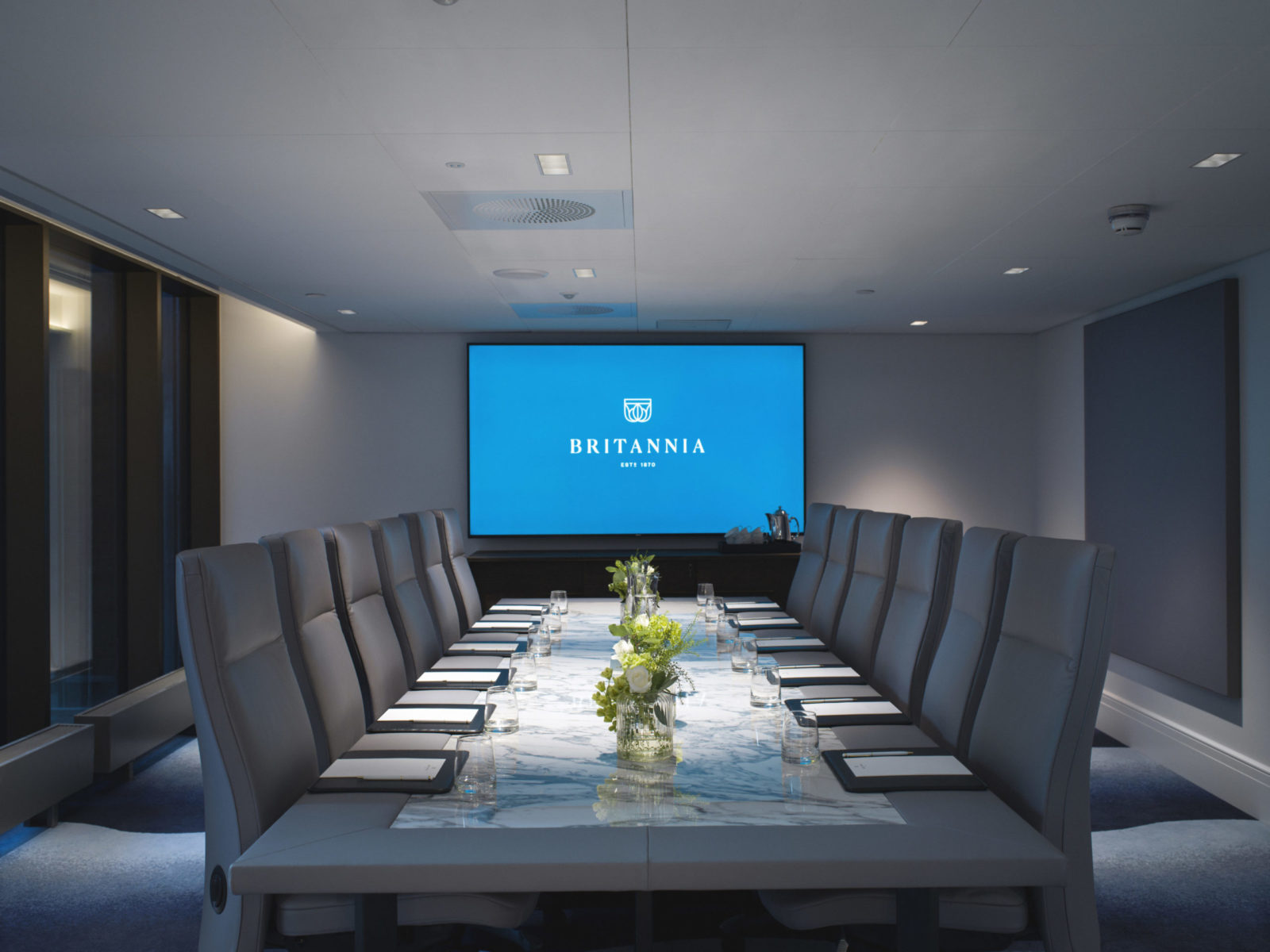 Conference room at Britannia Hotel with big screen, long table for 12 people