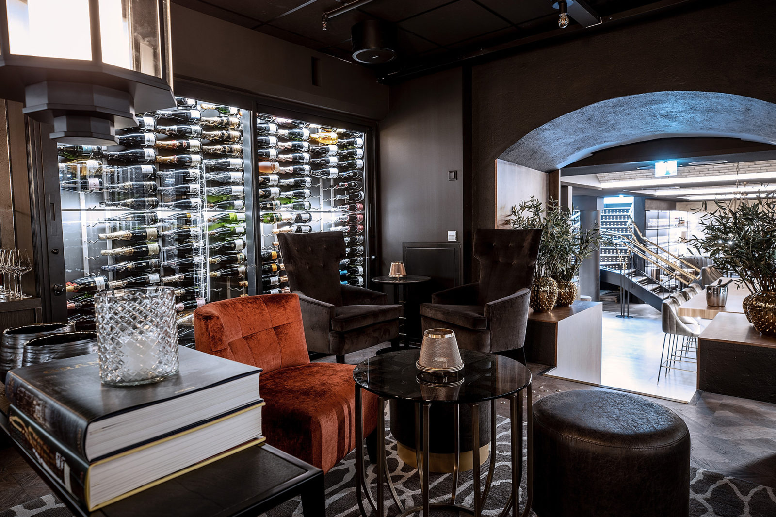 Velour chairs and small tables for wine serving, walls covered with wine bottles