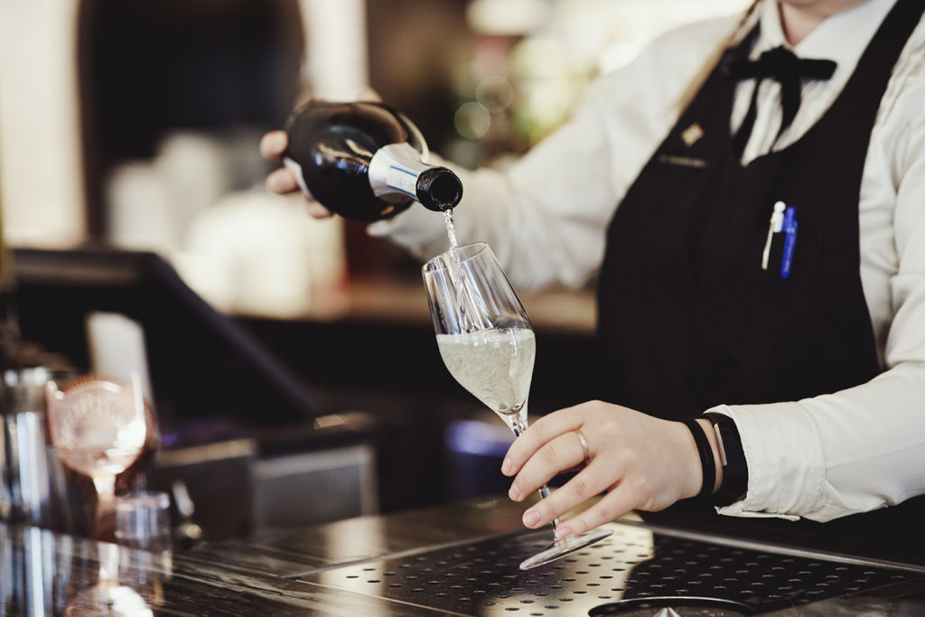 pouring Britannia House Champagne into a tall glass in the Brasserie restaurant 