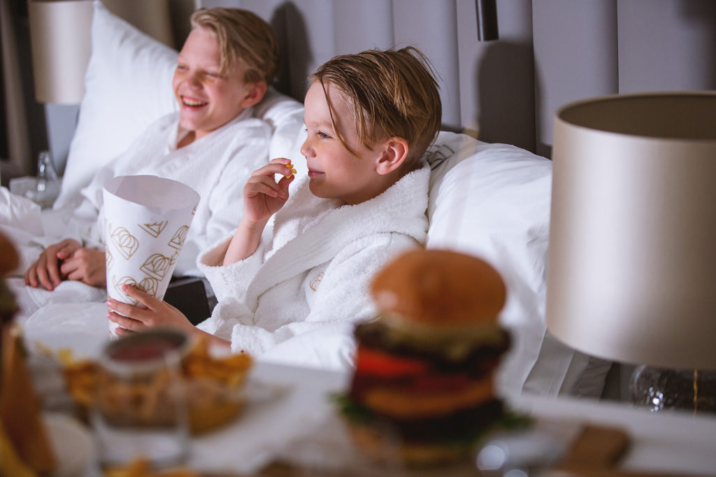 To gutter som nyter roomservice fra senga på Britannia Hotel i Trondheim